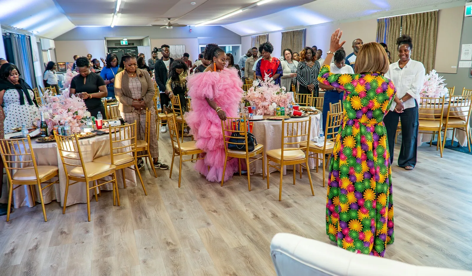 Worshippers standing in a decorated hall, one woman raising her hand in worship